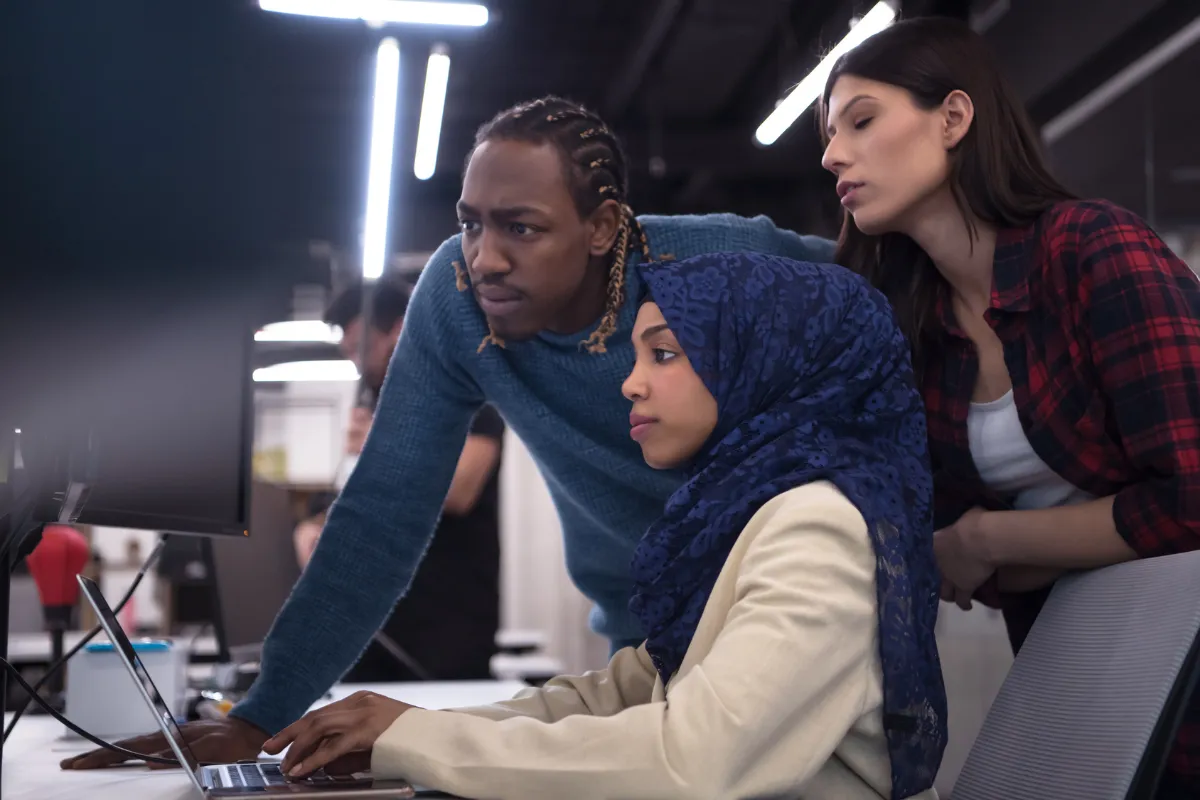 Engineers gathered around a laptop in an office